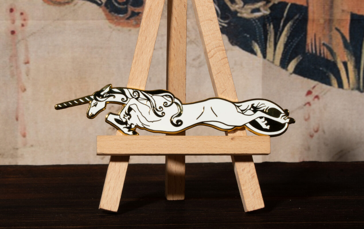 White unicorn enamel pin on mini easel